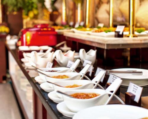 a buffet line with white bowls and plates of food at Asian Ruby Hotel & Spa - 122F Bui Thi Xuân Street in Ho Chi Minh City