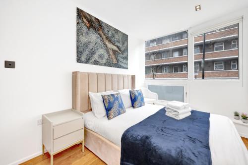 a white bedroom with a bed and a window at Loft-style 3 bed apartment in Hoxton London! in London
