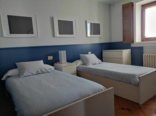 two beds in a room with blue walls at Casa Camino Santiago-Fisterra in Amés