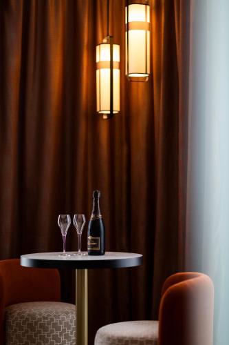 a table with two wine glasses and a bottle on it at Hôtel & Spa Oceania Le Conti in Brest