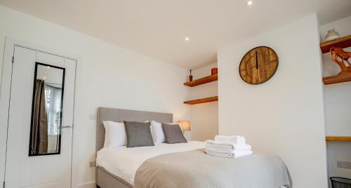 a bedroom with two beds and a clock on the wall at Modern flat with garden in city centre in Hereford