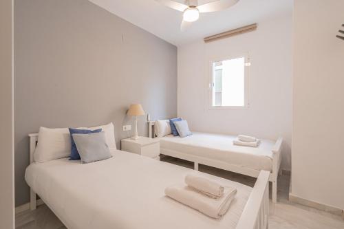 Habitación blanca con 2 camas y ventana en Stay U-nique Apartment Fernando Católico, en Málaga