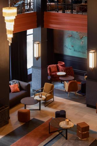a lobby with couches and tables and chairs at Hôtel & Spa Oceania Le Conti in Brest