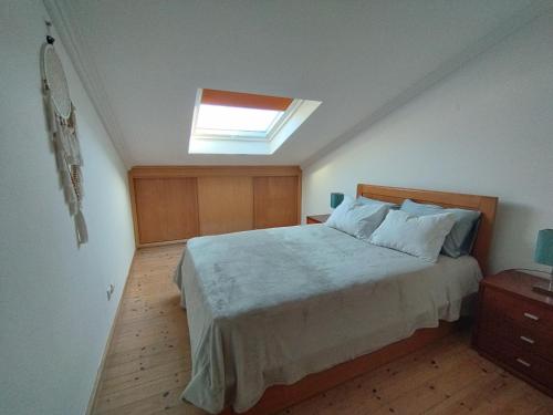a bedroom with a large bed with a skylight at Porto Covo / Costa Alentejana in Porto Covo