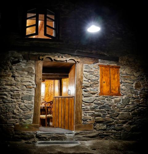 una casa de piedra con una luz encima en A casa dos carros en Folgoso