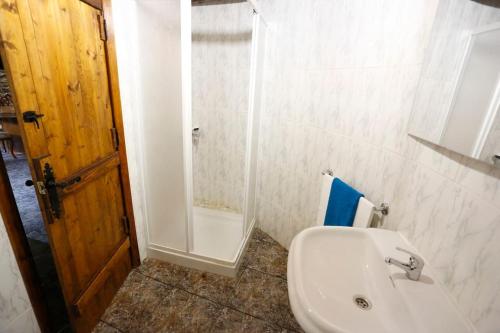 a bathroom with a white sink and a shower at A casa dos carros in Folgoso