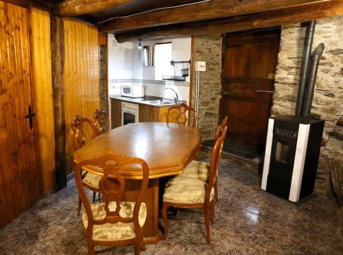 cocina con mesa de comedor de madera y sillas en A casa dos carros, en Folgoso