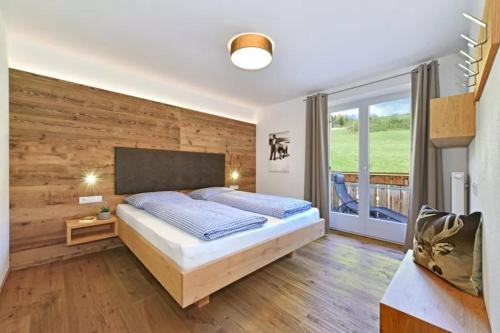 1 dormitorio con 1 cama y pared de madera en Jaiterhof Apartment Furchetta, en Villnoss