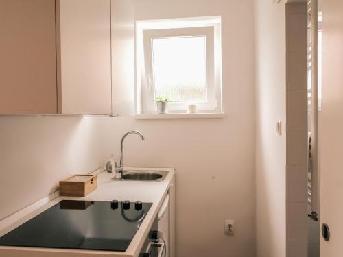 a white kitchen with a sink and a window at Studio apartmani Venium in Križevci