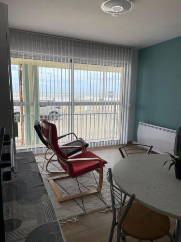 ベルク・シュル・メールにあるStudio à la plageのリビングルーム(椅子、テーブル付)、窓が備わります。