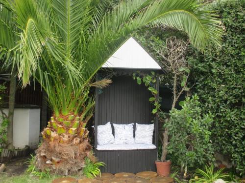 a bed in a garden with a palm tree at Mulligans Guest Lodge in Hermanus