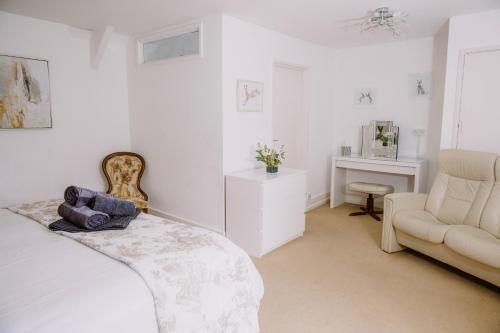 a white bedroom with a bed and a chair at Leygreen Farmhouse B&B in Beaulieu