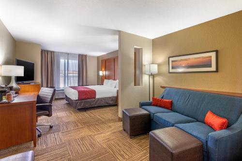 a hotel room with a bed and a blue couch at Comfort Suites Brunswick in Brunswick