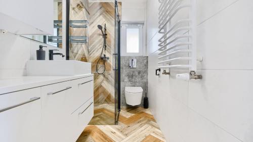 a white bathroom with a shower and a toilet at Apartamenty Sun & Snow Szafirowa in Mielno