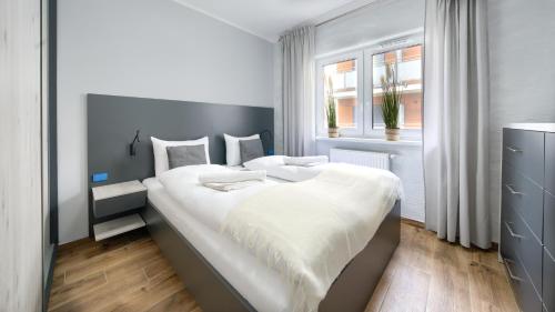 a bedroom with a large white bed with a window at Apartamenty Sun & Snow Szafirowa in Mielno