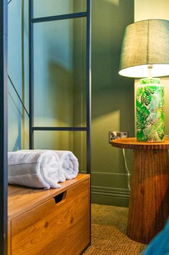 a room with a bed and a lamp and towels at Hestia House in Derry Londonderry