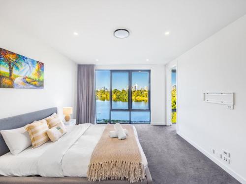 - une chambre blanche avec un grand lit et une grande fenêtre dans l'établissement Luxurious 4BR Waterfront Retreat in Mermaid Waters, à Gold Coast