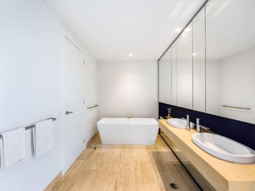 La salle de bains est pourvue de 2 lavabos et d'un grand miroir. dans l'établissement Luxurious 4BR Waterfront Retreat in Mermaid Waters, à Gold Coast