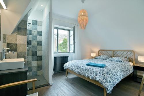 a bedroom with a bed and a bathroom with a sink at La Saleya - Maison à moins d'un km de la plage in Dinard