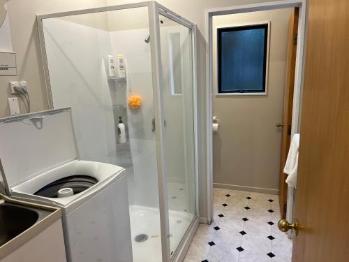 a bathroom with a shower with a washing machine at Acacia Views - Acacia Bay Holiday Home in Taupo