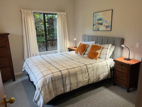 a bedroom with a bed with orange pillows and a window at Acacia Views - Acacia Bay Holiday Home in Taupo