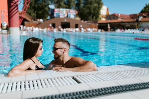 un hombre y una mujer sentados en una piscina en Rozmaring Apartmanház, en Mórahalom