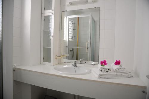 Résidence Tropicale في لو مول: حمام أبيض مع حوض ومرآة