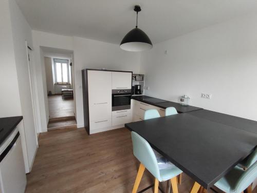 une cuisine avec un comptoir noir et une table dans l'établissement Agréable maison de bourg, à Saint-Macaire-en-Mauges