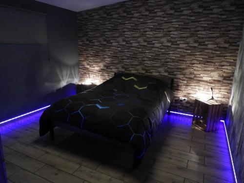um quarto escuro com uma cama com luzes azuis em Hors du temps em Ourt