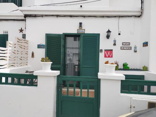 a green door on a white building with green shutters at Casa Leiva in Punta Mujeres