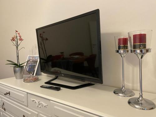 a flat screen tv sitting on a dresser with two wine glasses at A Casa di Luca in Faenza