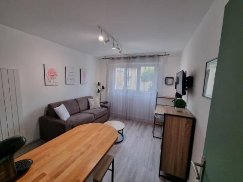 un salon avec un canapé et une table dans l'établissement Echappée en bord de mer - studio à la plage !, à Courseulles-sur-Mer