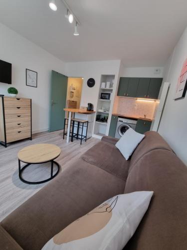 un salon avec un canapé et une cuisine dans l'établissement Echappée en bord de mer - studio à la plage !, à Courseulles-sur-Mer