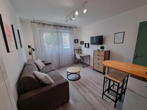 un salon avec un canapé et une table dans l'établissement Echappée en bord de mer - studio à la plage !, à Courseulles-sur-Mer