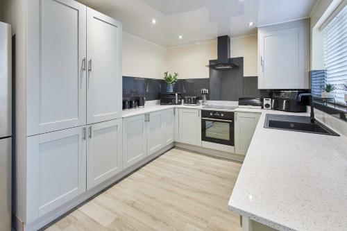 uma cozinha com armários brancos e piso em madeira em Host & Stay - Violet's View em Whitby