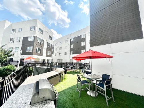 a patio with a table and chairs and a red umbrella at Hillsborough Street Flat in Raleigh