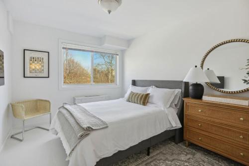 a white bedroom with a bed and a mirror at Crystal City Boutique Flats 2BR - Free Parking 204 in Arlington