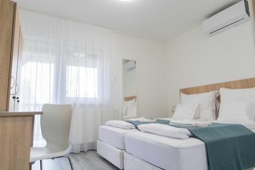 a white bedroom with a large bed with white pillows at Farkas Villa Apartmanok in Mórahalom