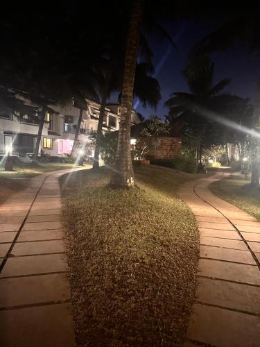 a sidewalk with two palm trees next to a street at Riviera Hermitage in Arpora