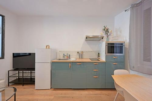 La cuisine est équipée de placards bleus et d'un réfrigérateur blanc. dans l'établissement Appart LeNA - Proche Théatres et Place des corps saints - Wi-Fi, à Avignon