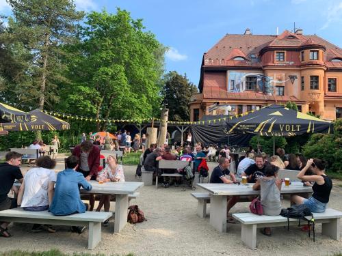 eine Gruppe von Menschen, die an Picknicktischen in einem Park sitzen in der Unterkunft Penzion Pivovar Volt in Jablonec nad Nisou