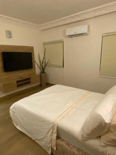 1 dormitorio con 1 cama blanca y TV de pantalla plana en BEDWELL HOMES, en Lagos