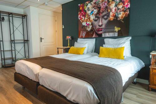 a bedroom with a large bed with a painting on the wall at De Klomp Charme Hotel & Restaurant in Vilsteren
