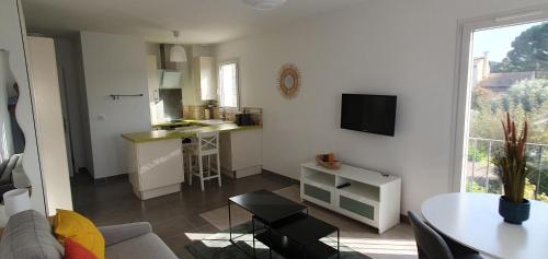 Il comprend un salon blanc avec une table et une cuisine. dans l'établissement 1 studio RDC et 1 studio 1er étage hauts de villeneuve les Avignon, à Villeneuve-lès-Avignon