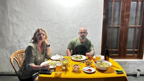 a man and a woman sitting at a yellow table with food at ARANI HOMESTAY in Polonnaruwa