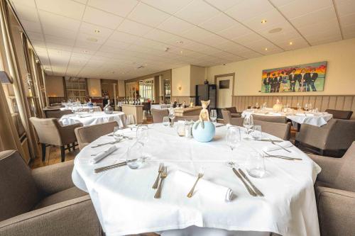 a dining room with white tables and chairs at De Klomp Charme Hotel & Restaurant in Vilsteren