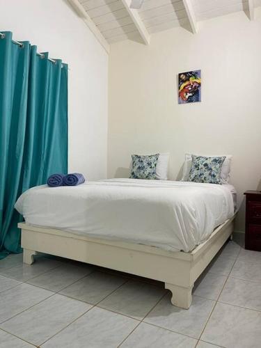 1 dormitorio con cama blanca y cortinas azules en Casita de 2 habitaciones en Las Terrenas