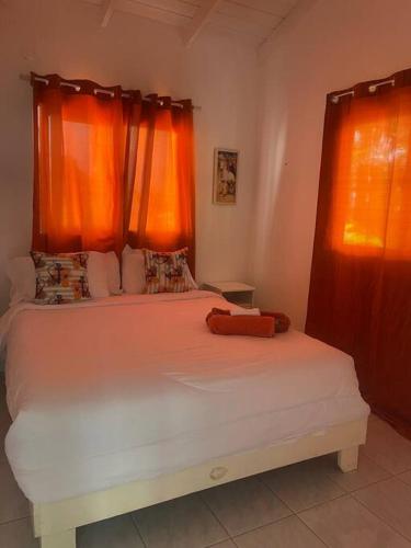 a bedroom with a white bed with orange curtains at Casita de 2 habitaciones in Las Terrenas