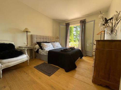 um quarto com uma cama, uma cadeira e uma janela em Carolienne em Vallauris