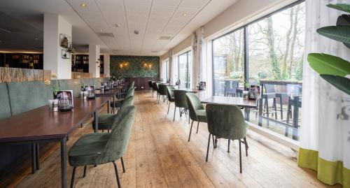 a restaurant with wooden tables and green chairs at Fletcher Hotel Restaurant Doorwerth - Arnhem in Doorwerth